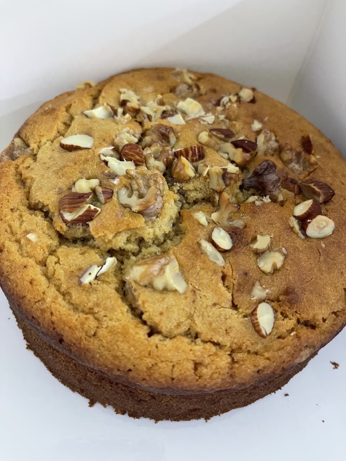 A simple, unfrosted homemade cake topped with chopped nuts