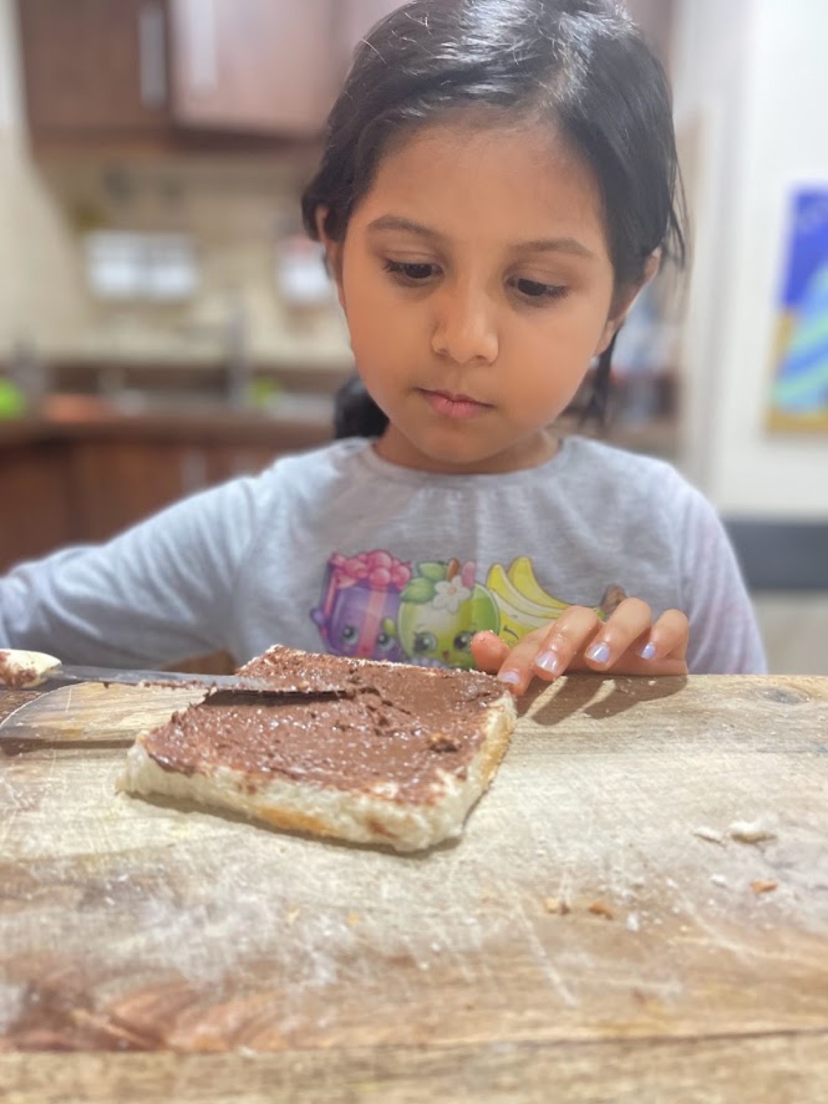 Vedhica carefully spreading Nutella onto a slice of bread