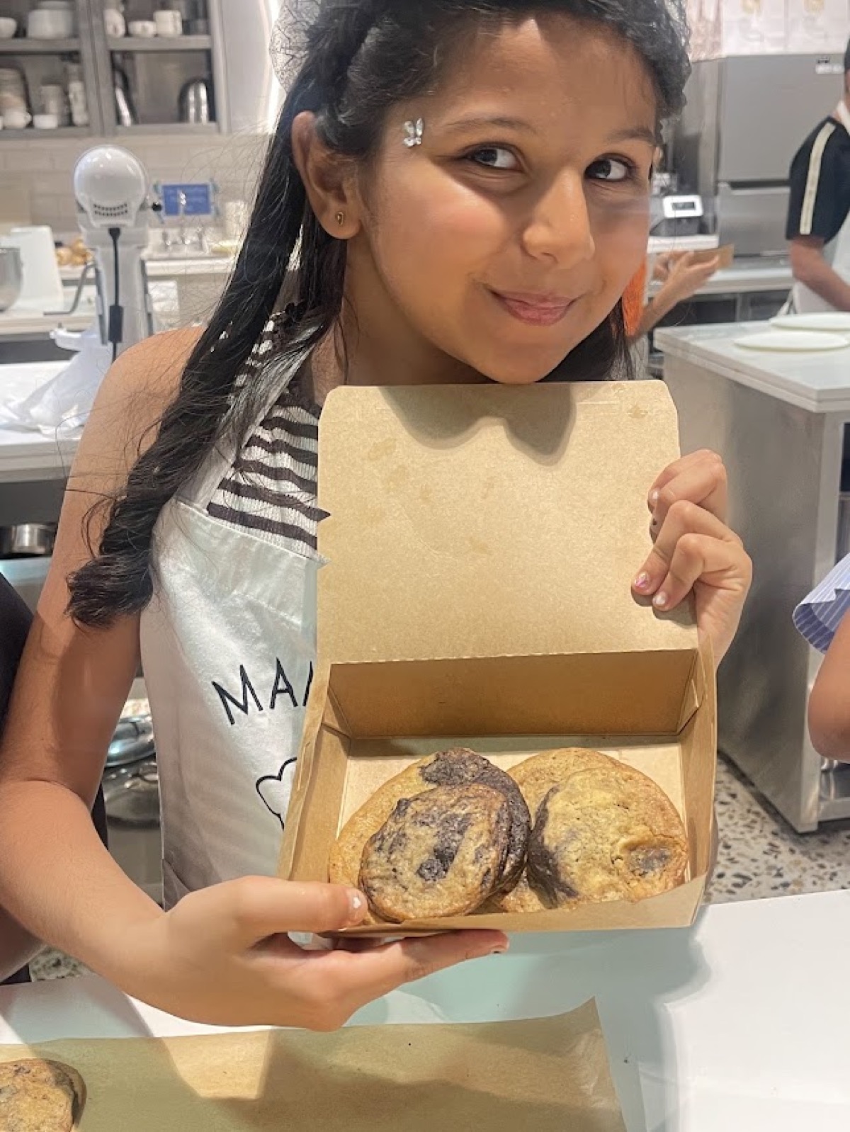 Vedhica holding a box of freshly baked chocolate chip cookies