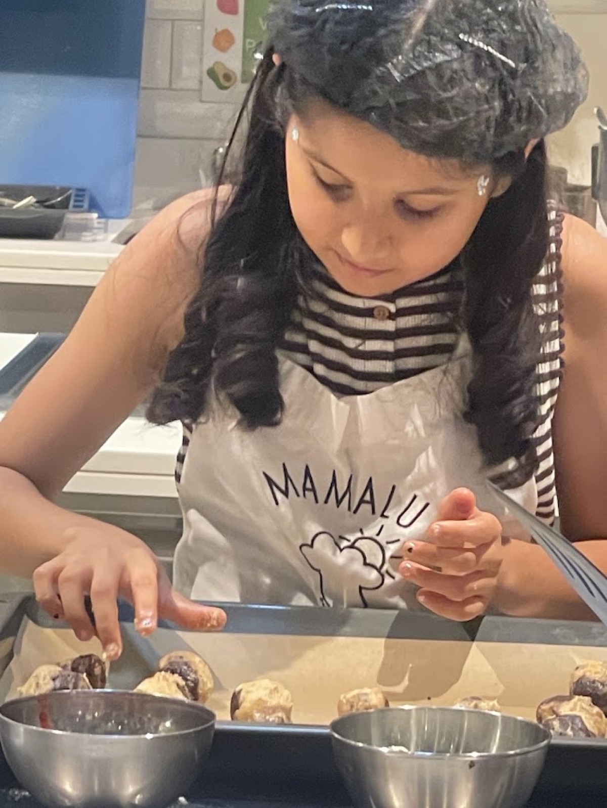 Vedhica placing rounded spoonfuls of cookie dough onto a lined baking tray