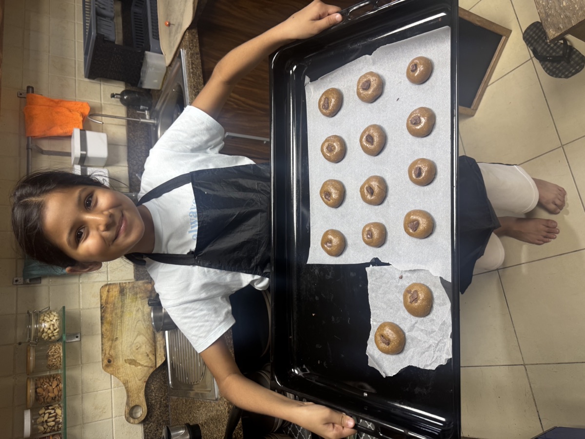 Vedhica holding a tray of cookie dough she rolled, ready for the oven