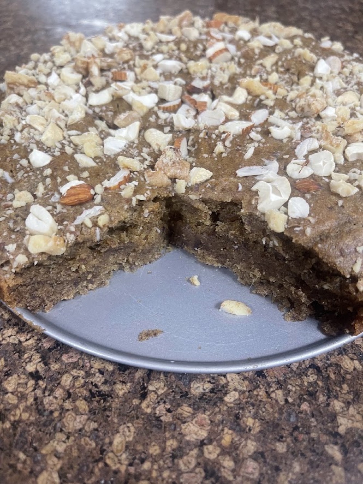 A nut-topped almond cake with one slice taken out
