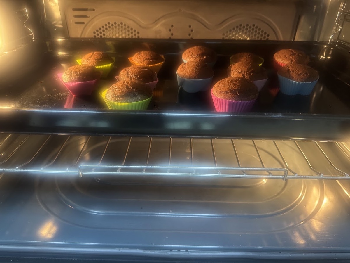 A tray of chocolate cupcakes in colourful cases baking inside the oven